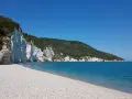 Scogliera bianca a picco sul mare turchese, con una spiaggia di ciottoli bianchi. Un angolo di paradiso, la spiaggia bianca Puglia.