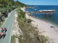 Ciclisti sulla pista ciclabile lungo mare, con i trabocchi che caratterizzano la costa dei Trabocchi cosa vedere. Spiaggia di ciottoli e mare azzurro.