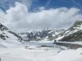 Paesaggio innevato al Gran San Bernardo con edifici storici e montagne maestose sotto un cielo nuvoloso.