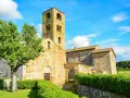 Antico campanile romanico e edifici in pietra nel **Sovicille centro storico**, con un albero verdeggiante e cielo azzurro.
