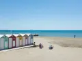 Colorate cabine sulla spiaggia di Ostia, mare di Roma, con persone che si rilassano al sole.