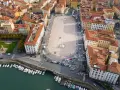 Vista aerea della **Piazza della Repubblica a Livorno**, con edifici storici, un monumento centrale, auto e barche ormeggiate nel canale.