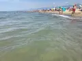 Onde leggere accarezzano la **spiaggia libera Viareggio**, affollata di bagnanti sotto ombrelloni colorati.