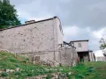 Antico eremo di Cerbaiolo, con muri in pietra grezza e vegetazione rigogliosa che sale sul pendio.