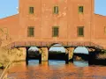 Edificio storico con ponticello ad archi sull'acqua, un'idea di cosa vedere vicino a Castiglione della Pescaia.