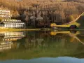 Hotel Cristallo sul Passo del Cerreto, riflesso sull'acqua calma di un lago circondato da boschi autunnali.