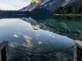 Lago alpino con riflessi di montagne e nuvole, un pontile in legno invita a contemplare la bellezza del Val di Non.