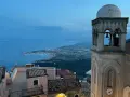 Castelmola cosa vedere: vista panoramica sul mare e sulla costa siciliana, con un campanile in primo piano.