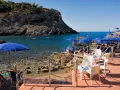 Le argentario spiagge più belle, con ombrelloni blu e lettini su una terrazza in legno, affacciate sul mare cristallino.