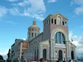 Imponente Santuario di Tindari con cupola dorata e facciata decorata, sotto un cielo azzurro con nuvole bianche.