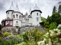 Un fiabesco castello in pietra, tra i castelli Val d'Aosta, circondato da un giardino fiorito e boschi rigogliosi.