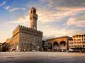 Il maestoso Palazzo Vecchio domina Piazza della Signoria, con la sua torre imponente che svetta sotto un cielo al tramonto.