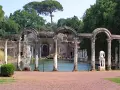 Resti archeologici di Villa Adriana con statue classiche e un laghetto, immersi nel verde.