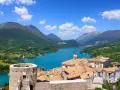 Villetta Barrea: cosa vedere? Un borgo con torre medievale, tetti rossi e un lago azzurro circondato da montagne verdi.
