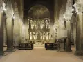 Interno della pieve di Gropina, con imponenti colonne, archi e un'abside decorata.