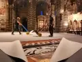 Due operai spostano carrelli sul magnifico pavimento del Duomo di Siena, mentre un telo protettivo è parzialmente sollevato, rivelando i dettagli artistici.