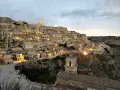 I Sassi di Matera illuminati al crepuscolo, un panorama mozzafiato di case scavate nella roccia e chiese antiche.