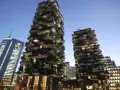 Il Bosco Verticale di Milano, con i suoi grattacieli ricoperti di alberi e piante, si staglia contro il cielo serale.
