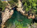 Bagni Regina Giovanna: una baia nascosta con acque cristalline, rocce scolpite e vegetazione lussureggiante. Persone si godono il sole e nuotano.
