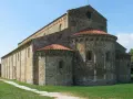 Antica basilica romanica di San Piero a Grado, con absidi semicircolari e tetto in cotto, immersa nel verde.