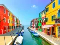 Coloratissime case affacciate su un canale, con barche ormeggiate. Un'immagine che invita a scoprire le splendide venezia isole da visitare.
