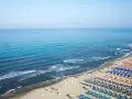 Ampia spiaggia libera al Lido di Camaiore, con file ordinate di ombrelloni e lettini che si estendono verso il mare azzurro.