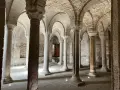 Interno dell'abbazia di San Salvatore: un corridoio con volte a crociera e colonne in pietra, che evocano secoli di storia.