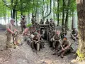 Soldati in uniforme militare, armati e pronti, si riposano in un bosco, forse durante una sosta al passo del giogo.