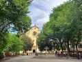 Piazza Santo Spirito a Firenze, con la chiesa sullo sfondo, una fontana al centro e alberi rigogliosi che incorniciano la scena.