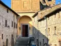 Chianni cosa vedere: un vicolo con case in pietra, una chiesa con un grande portale in legno e una scalinata.