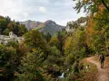 Sentiero nel Parco Nazionale delle Foreste Casentinesi Monte Falterona e Campigna, con un escursionista che cammina tra boschi autunnali e antichi edifici storici.