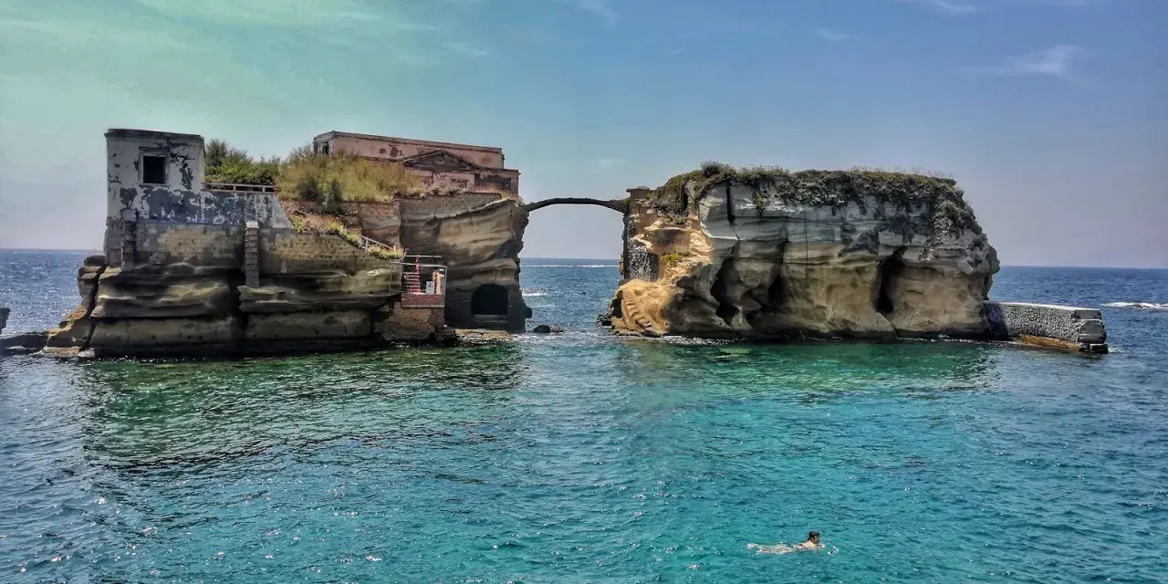 L'isola di Gaiola, con le sue rovine suggestive e il mare cristallino, accoglie bagnanti e nuotatori in una giornata di sole.
