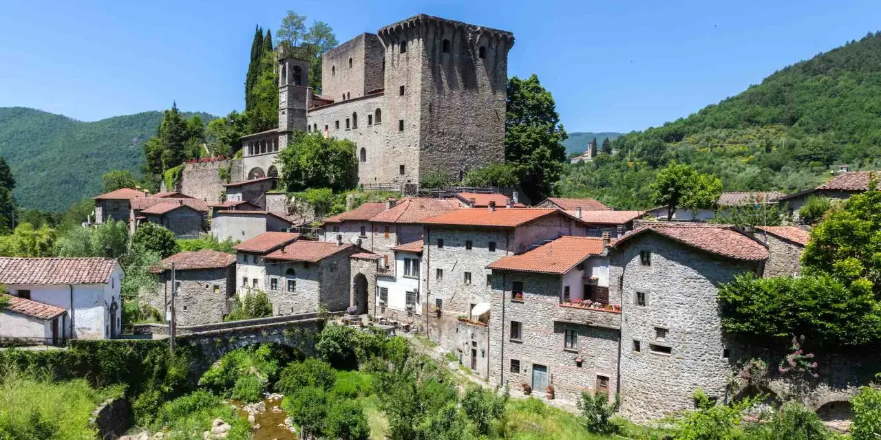 Fivizzano cosa vedere: un borgo medievale con castello, case in pietra e un ponte ad arco su un ruscello.