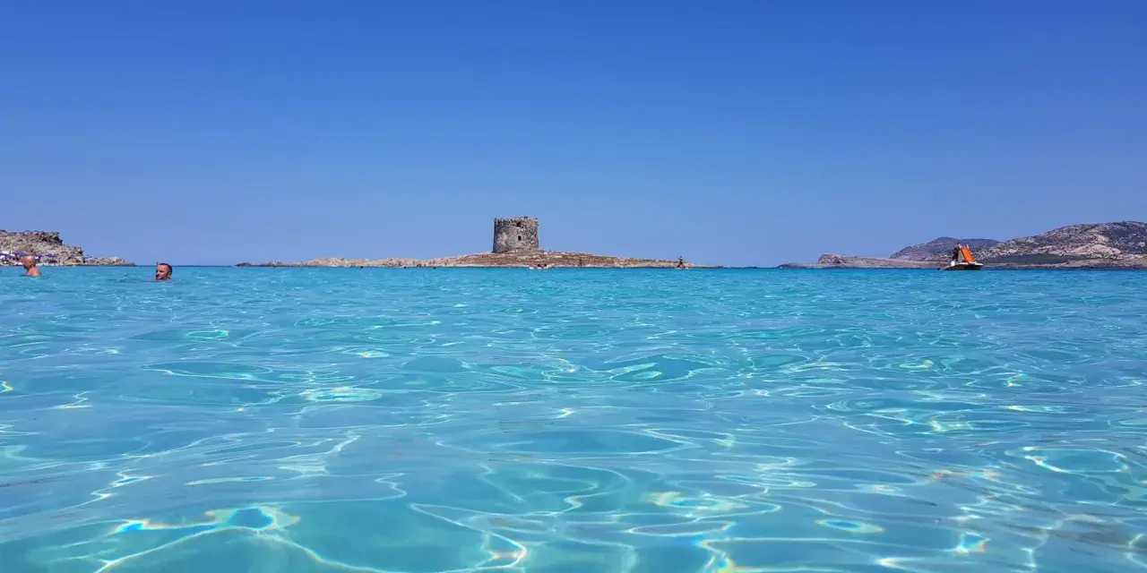 Acque cristalline e un'antica torre su un isolotto: ecco la spiaggia più bella d'Italia, un paradiso azzurro.