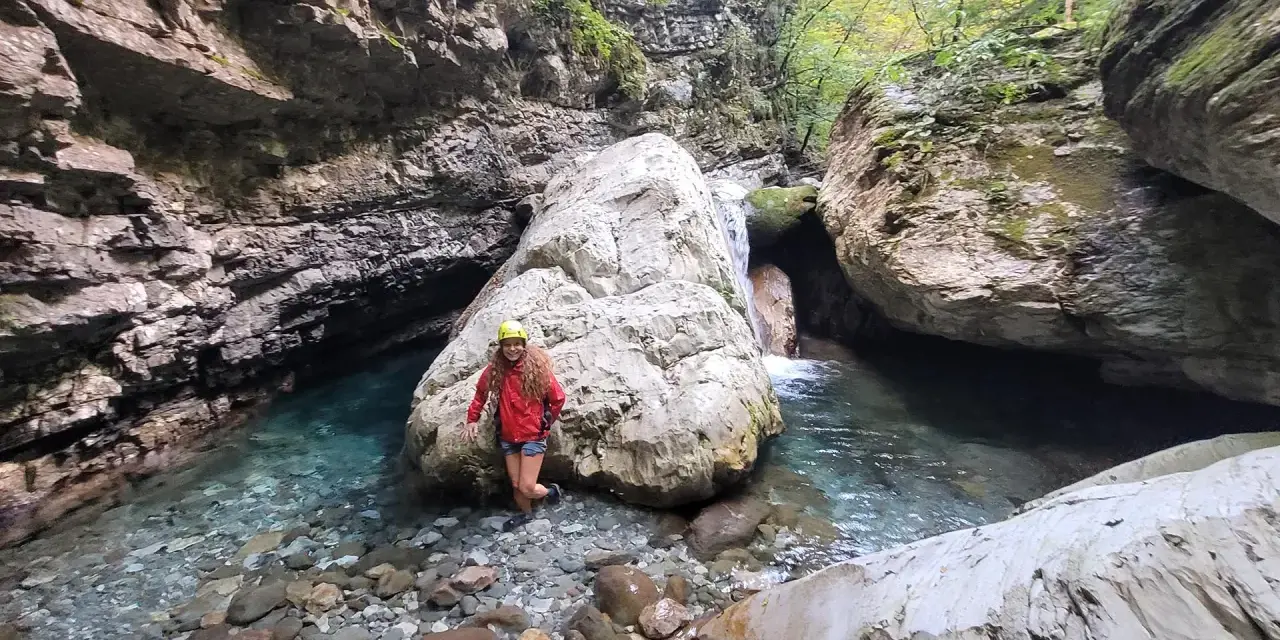 Esploratrice sorridente nel canyon dell'Orrido di Botri, tra rocce imponenti e acque cristalline.