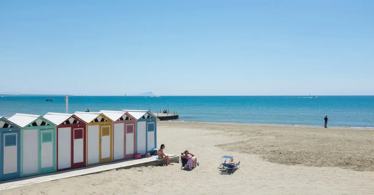Colorate cabine sulla spiaggia di Ostia, mare di Roma, con persone che si rilassano al sole.