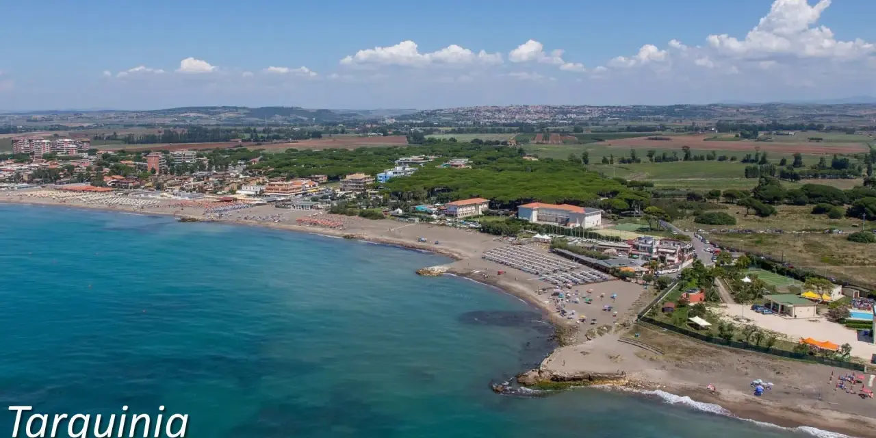 Vista aerea del lido di Tarquinia con spiaggia attrezzata, mare azzurro e pineta.