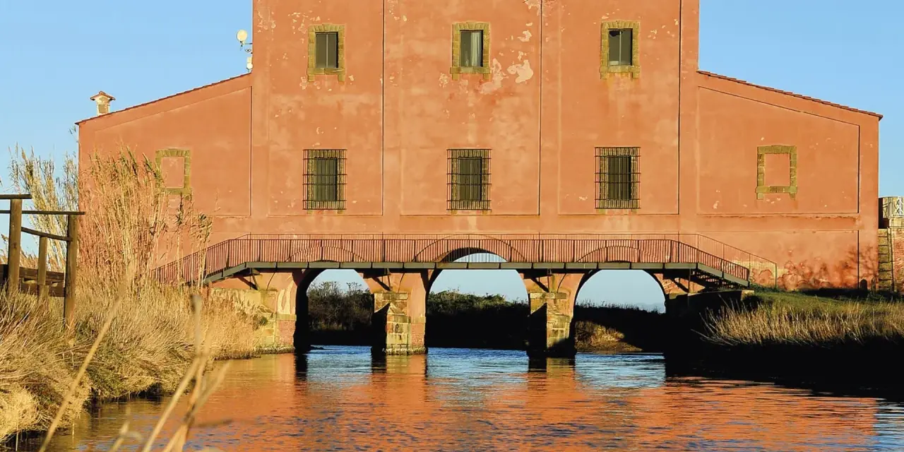 Edificio storico con ponticello ad archi sull'acqua, un'idea di cosa vedere vicino a Castiglione della Pescaia.