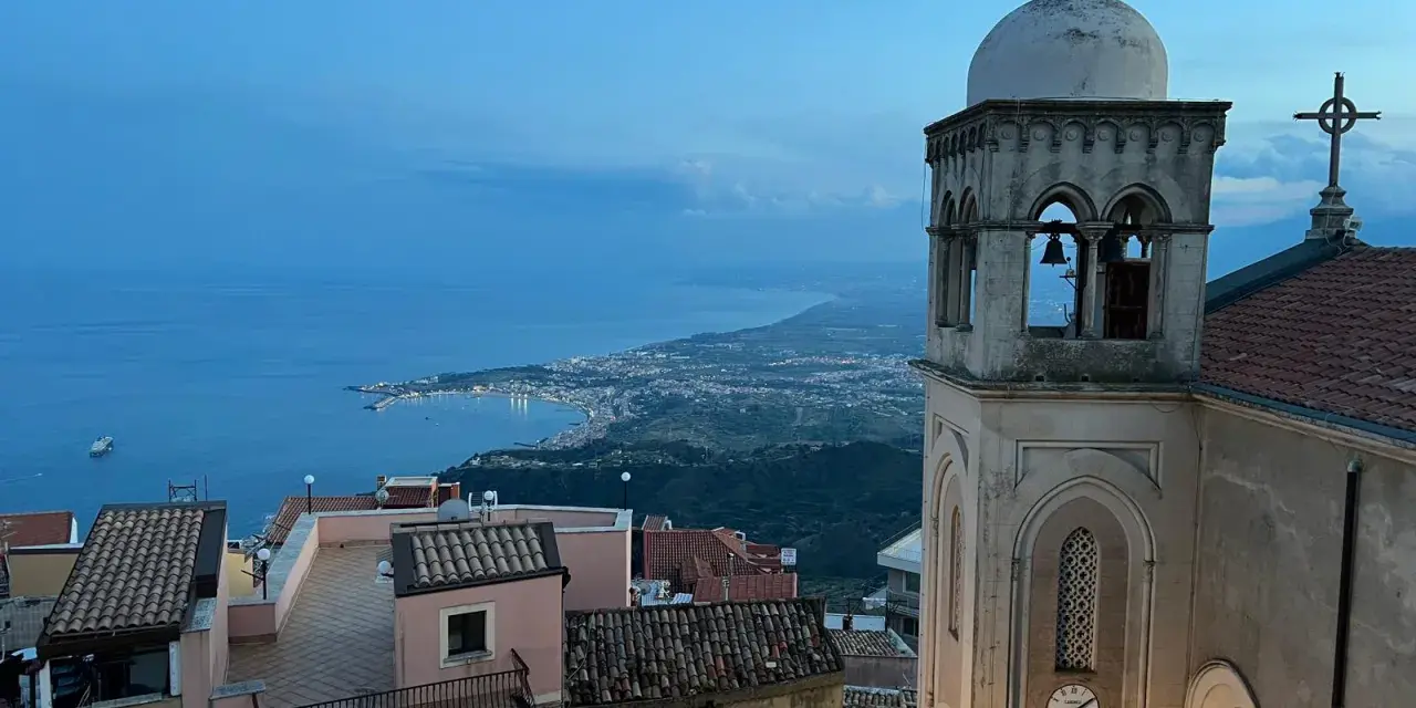 Castelmola cosa vedere: vista panoramica sul mare e sulla costa siciliana, con un campanile in primo piano.