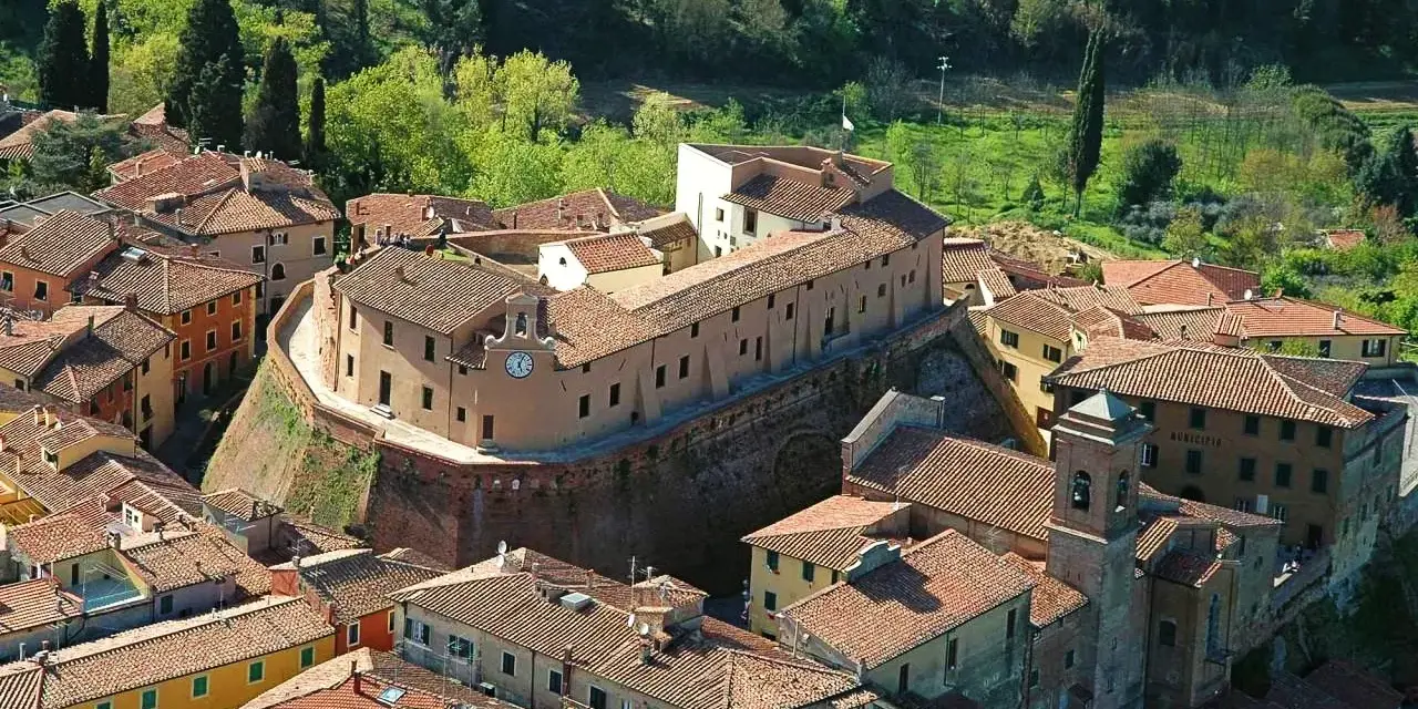 Borgo fortificato con case in pietra e tetti rossi, un campanile e un orologio. Un'ottima meta per scoprire cosa vedere vicino Pisa.