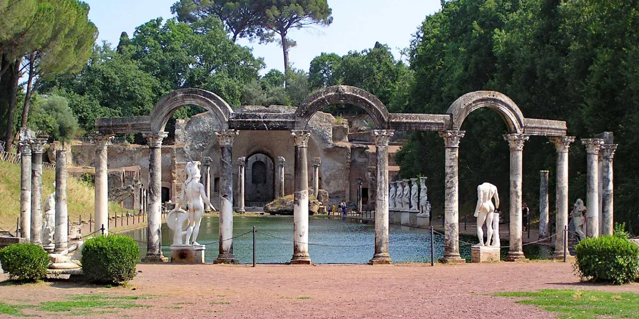 Resti archeologici di Villa Adriana con statue classiche e un laghetto, immersi nel verde.