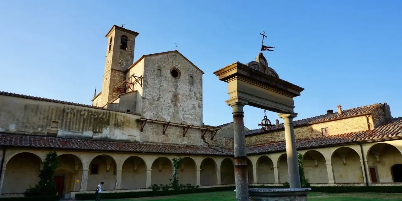 Cortile con pozzo e campanile di Castel Nuovo Berardenga, sotto un cielo azzurro.