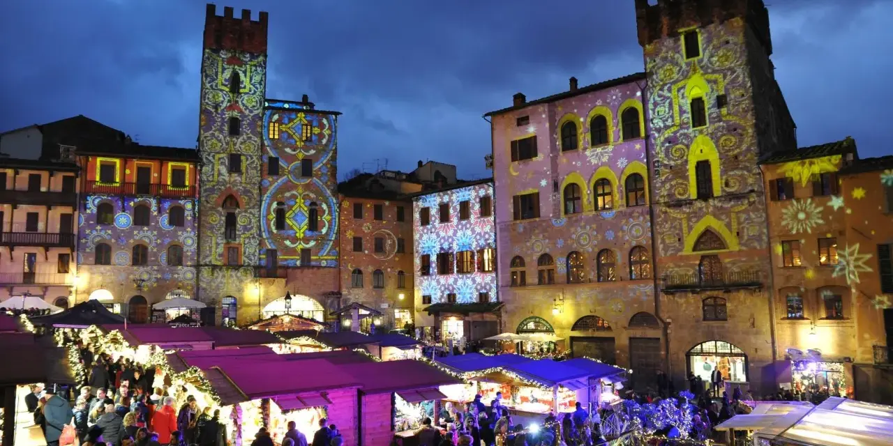 Mercatino natalizio ad Arezzo, con palazzi illuminati da proiezioni colorate. Vale la pena visitare Arezzo per questa magica atmosfera.