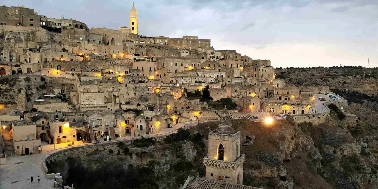 I Sassi di Matera illuminati al crepuscolo, un panorama mozzafiato di case scavate nella roccia e chiese antiche.