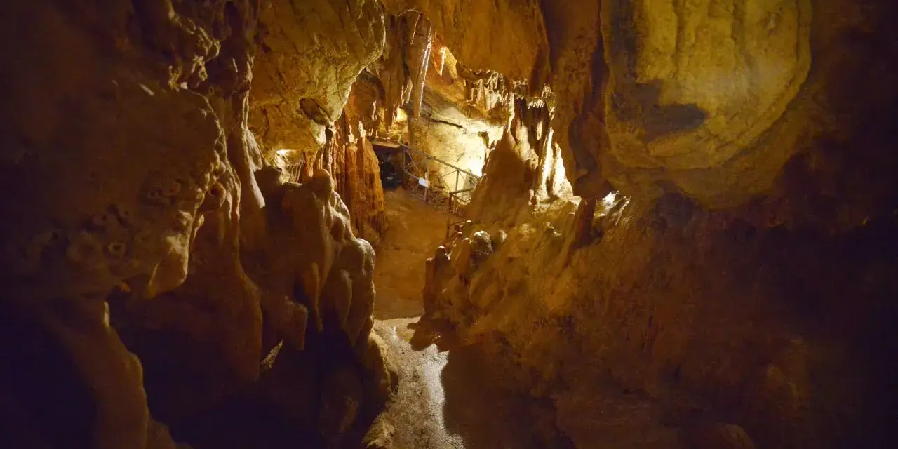 Interno della grotta Maona a Montecatini, con stalattiti e stalagmiti illuminate.