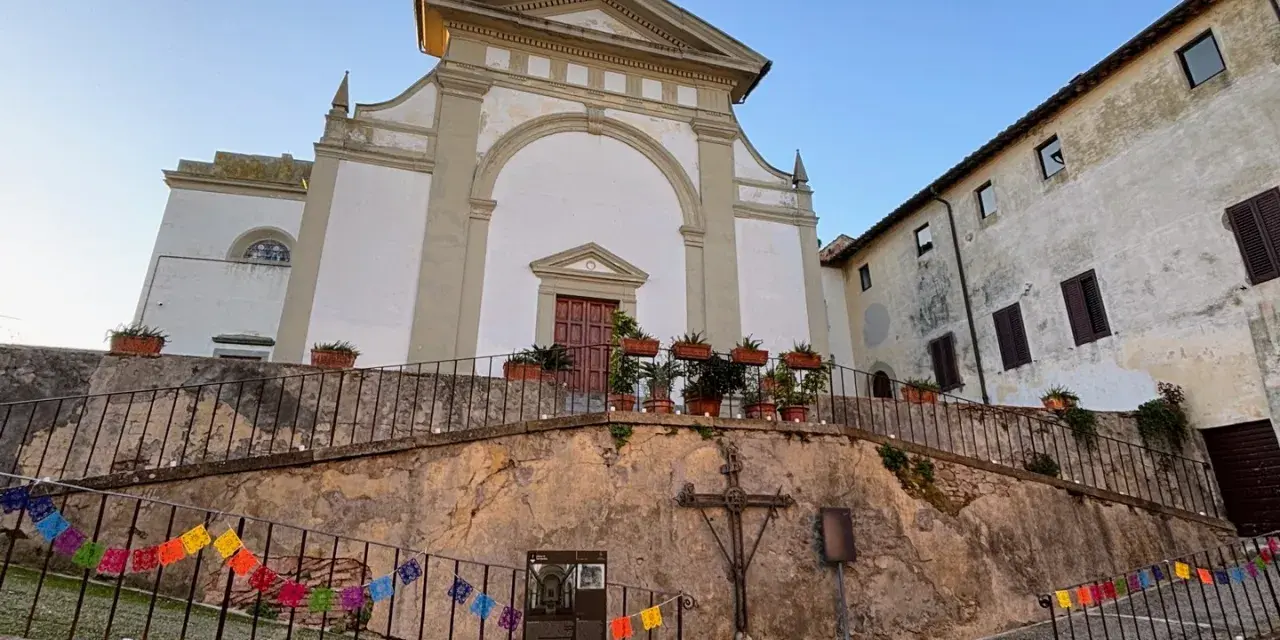 Terricciola cosa vedere: la chiesa parrocchiale domina la piazza, con un'antica croce e festoni colorati che creano un'atmosfera suggestiva.