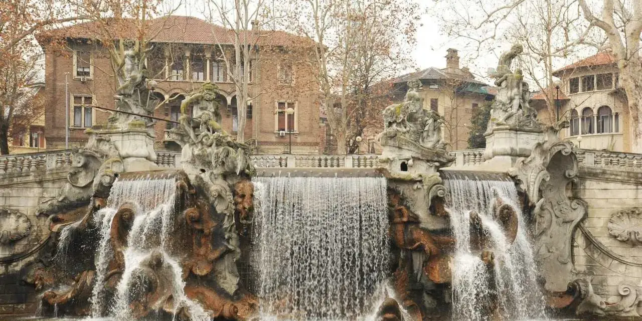 Fontana monumentale nel Parco del Valentino, con statue e cascate d'acqua che scendono su rocce scultoree.