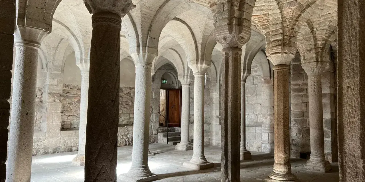 Interno dell'abbazia di San Salvatore: un corridoio con volte a crociera e colonne in pietra, che evocano secoli di storia.