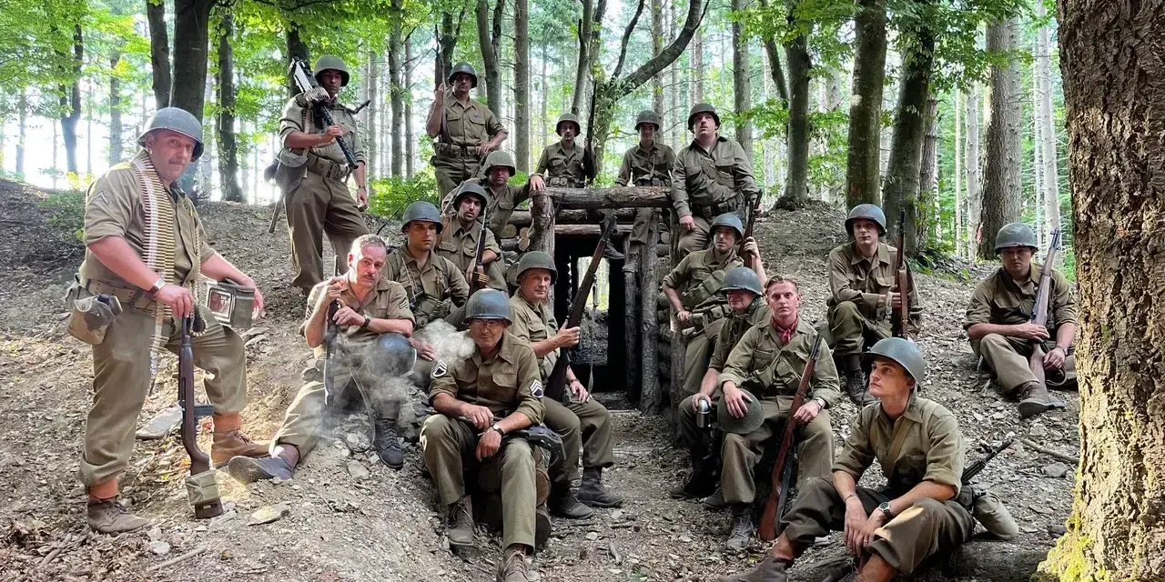 Soldati in uniforme militare, armati e pronti, si riposano in un bosco, forse durante una sosta al passo del giogo.