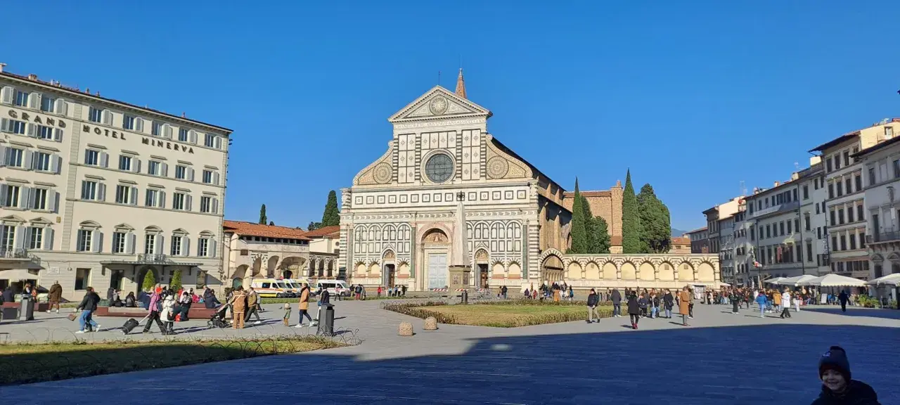 Piazza Santa Maria Novella a Firenze, con la facciata rinascimentale della basilique santa maria novella in primo piano e il Grand Hotel Minerva sulla sinistra.